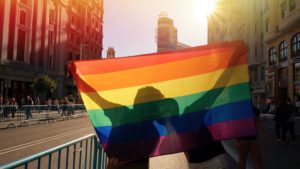 Photo of a couple holding up a gay pride flag