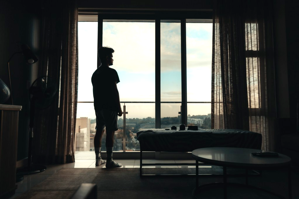 Silhouette of a young man standing outside an apartment window