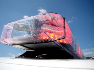 A close up of a blinking lit red emergency vehicle light on top of a police car.