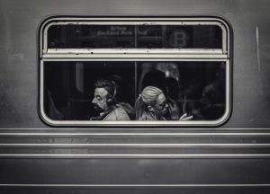 A black and white photo of a man and woman sitting back-to-back in a train car.